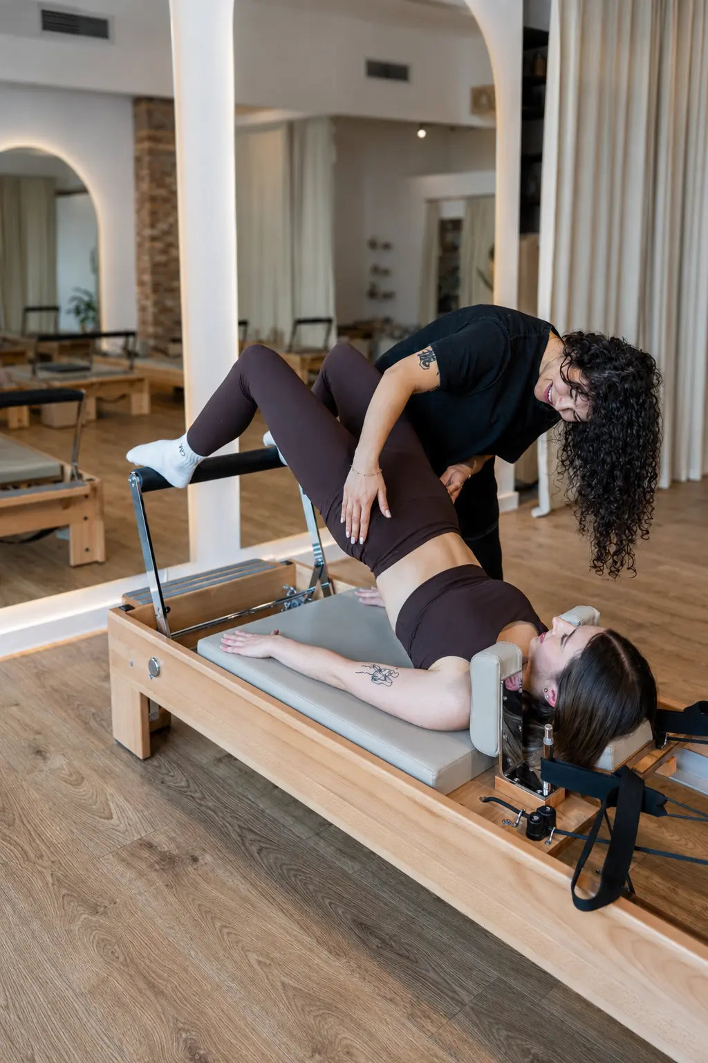 Instruktorka koryguje ustawienie ciała klientki podczas zajęć pilates